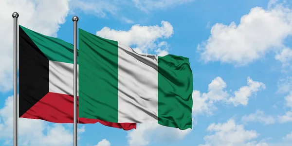 Kuwait e a bandeira da Nigéria agitando no vento contra o céu azul nublado branco juntos. Conceito de diplomacia, relações internacionais . — Fotografia de Stock
