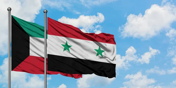 Bandera de Kuwait y Siria ondeando en el viento contra el cielo azul nublado blanco juntos. Concepto diplomático, relaciones internacionales . — Foto de Stock