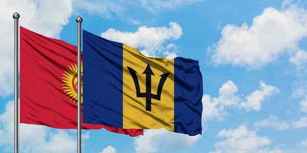 Bandera de Kirguistán y Barbados ondeando en el viento contra el cielo azul nublado blanco juntos. Concepto diplomático, relaciones internacionales . — Foto de Stock