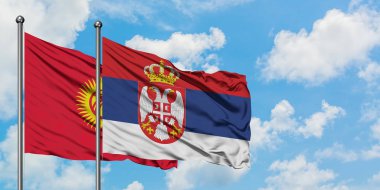 Kırgızistan ve Sırbistan bayrağı birlikte beyaz bulutlu mavi gökyüzüne karşı rüzgarda sallayarak. Diplomasi kavramı, uluslararası ilişkiler.