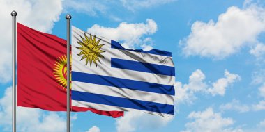 Kırgızistan ve Uruguay bayrağı birlikte beyaz bulutlu mavi gökyüzüne karşı rüzgarsal sallayarak. Diplomasi kavramı, uluslararası ilişkiler.