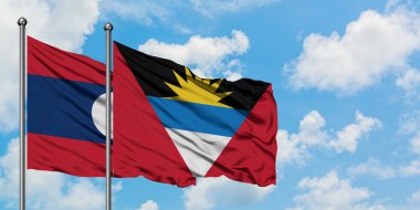 Laos ve Antigua ve Barbuda bayrağı birlikte beyaz bulutlu mavi gökyüzüne karşı rüzgarda sallayarak. Diplomasi kavramı, uluslararası ilişkiler.