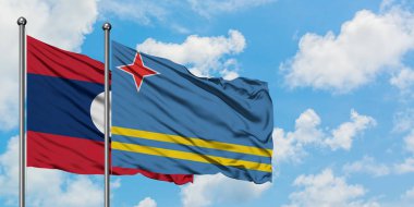 Laos ve Aruba bayrağı birlikte beyaz bulutlu mavi gökyüzüne karşı rüzgarda sallayarak. Diplomasi kavramı, uluslararası ilişkiler.