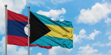 Laos ve Bahamalar bayrağı birlikte beyaz bulutlu mavi gökyüzüne karşı rüzgarda sallayarak. Diplomasi kavramı, uluslararası ilişkiler.