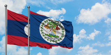 Laos ve Belize bayrağı birlikte beyaz bulutlu mavi gökyüzüne karşı rüzgarda sallayarak. Diplomasi kavramı, uluslararası ilişkiler.