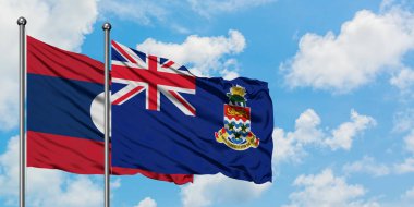 Laos ve Cayman Adaları bayrağı birlikte beyaz bulutlu mavi gökyüzüne karşı rüzgarda sallayarak. Diplomasi kavramı, uluslararası ilişkiler.