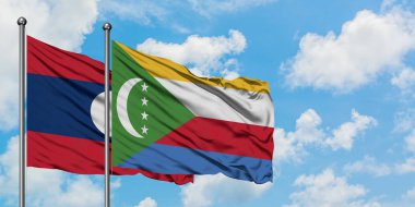 Laos ve Komorbayrağı birlikte beyaz bulutlu mavi gökyüzüne karşı rüzgarda sallayarak. Diplomasi kavramı, uluslararası ilişkiler.