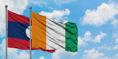 Laos ve Fildişi Sahili bayrağı birlikte beyaz bulutlu mavi gökyüzüne karşı rüzgarda sallayarak. Diplomasi kavramı, uluslararası ilişkiler.