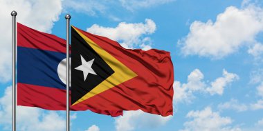 Laos ve Doğu Timor bayrağı birlikte beyaz bulutlu mavi gökyüzüne karşı rüzgarda sallayarak. Diplomasi kavramı, uluslararası ilişkiler.