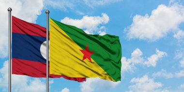 Laos ve Fransız Guyanası bayrağı birlikte beyaz bulutlu mavi gökyüzüne karşı rüzgarda sallayarak. Diplomasi kavramı, uluslararası ilişkiler.