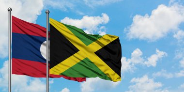 Laos ve Jamaika bayrağı birlikte beyaz bulutlu mavi gökyüzüne karşı rüzgarda sallayarak. Diplomasi kavramı, uluslararası ilişkiler.