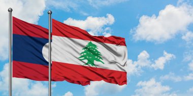 Laos ve Lübnan bayrağı birlikte beyaz bulutlu mavi gökyüzüne karşı rüzgarda sallayarak. Diplomasi kavramı, uluslararası ilişkiler.