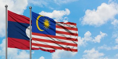 Laos ve Malezya bayrağı birlikte beyaz bulutlu mavi gökyüzüne karşı rüzgarda sallayarak. Diplomasi kavramı, uluslararası ilişkiler.