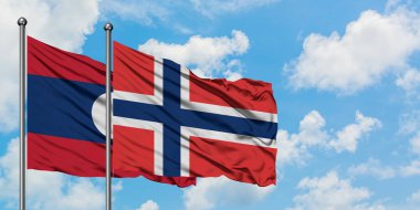 Laos ve Norveç bayrağı birlikte beyaz bulutlu mavi gökyüzüne karşı rüzgarda sallayarak. Diplomasi kavramı, uluslararası ilişkiler.