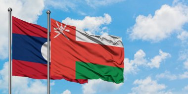 Laos ve Umman bayrağı birlikte beyaz bulutlu mavi gökyüzüne karşı rüzgarda sallayarak. Diplomasi kavramı, uluslararası ilişkiler.