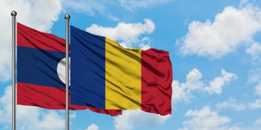 Laos ve Romanya bayrağı birlikte beyaz bulutlu mavi gökyüzüne karşı rüzgarda sallayarak. Diplomasi kavramı, uluslararası ilişkiler.