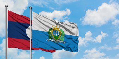 Laos ve San Marino bayrağı birlikte beyaz bulutlu mavi gökyüzüne karşı rüzgarda sallayarak. Diplomasi kavramı, uluslararası ilişkiler.