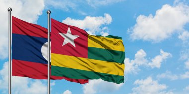 Laos ve Togo bayrağı birlikte beyaz bulutlu mavi gökyüzüne karşı rüzgarda sallayarak. Diplomasi kavramı, uluslararası ilişkiler.
