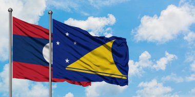 Laos ve Tokelau bayrağı birlikte beyaz bulutlu mavi gökyüzüne karşı rüzgarda sallayarak. Diplomasi kavramı, uluslararası ilişkiler.