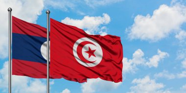 Laos ve Tunus bayrağı birlikte beyaz bulutlu mavi gökyüzüne karşı rüzgarda sallayarak. Diplomasi kavramı, uluslararası ilişkiler.