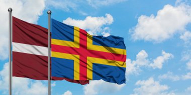 Letonya ve Aland Adaları bayrağı birlikte beyaz bulutlu mavi gökyüzüne karşı rüzgarsal sallayarak. Diplomasi kavramı, uluslararası ilişkiler.