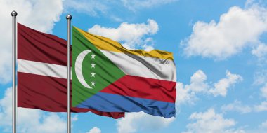 Letonya ve Komorbayrağı birlikte beyaz bulutlu mavi gökyüzüne karşı rüzgarda sallayarak. Diplomasi kavramı, uluslararası ilişkiler.