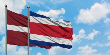 Letonya ve Kosta Rika bayrağı birlikte beyaz bulutlu mavi gökyüzüne karşı rüzgarda sallayarak. Diplomasi kavramı, uluslararası ilişkiler.