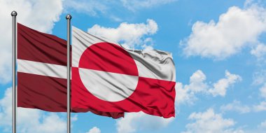 Letonya ve Grönland bayrağı birlikte beyaz bulutlu mavi gökyüzüne karşı rüzgarda sallayarak. Diplomasi kavramı, uluslararası ilişkiler.