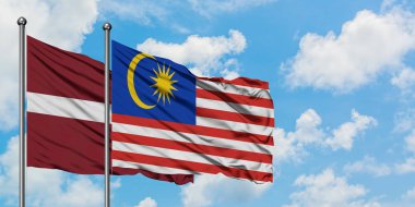 Letonya ve Malezya bayrağı birlikte beyaz bulutlu mavi gökyüzüne karşı rüzgarda sallayarak. Diplomasi kavramı, uluslararası ilişkiler.