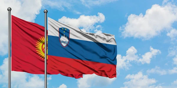 Kyrgyzstan and Slovenia flag waving in the wind against white cloudy blue sky together. Diplomacy concept, international relations.