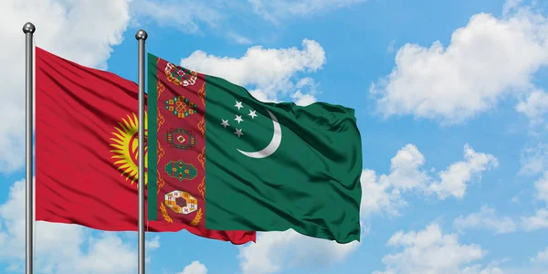 Bandera de Kirguistán y Turkmenistán ondeando en el viento contra el cielo azul nublado blanco juntos. Concepto diplomático, relaciones internacionales . — Foto de Stock
