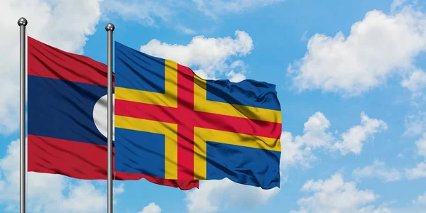 Laos and Aland Islands flag waving in the wind against white cloudy blue sky together. Diplomacy concept, international relations. — Stock Photo, Image