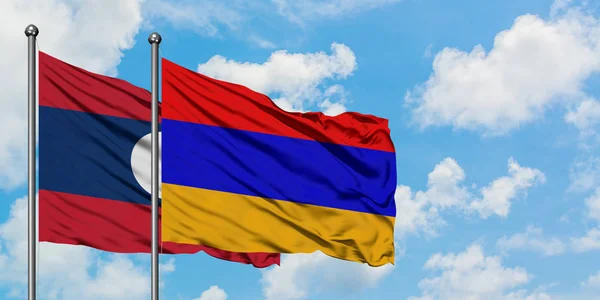 Bandera de Laos y Armenia ondeando en el viento contra el cielo azul nublado blanco juntos. Concepto diplomático, relaciones internacionales . — Foto de Stock