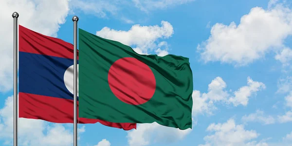 Bandera de Laos y Bangladesh ondeando en el viento contra el cielo azul nublado blanco juntos. Concepto diplomático, relaciones internacionales . — Foto de Stock