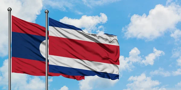 Лаос и флаг Коста-Рики вместе машут ветром против белого облачно-синего неба. Концепция дипломатии, международные отношения . — стоковое фото