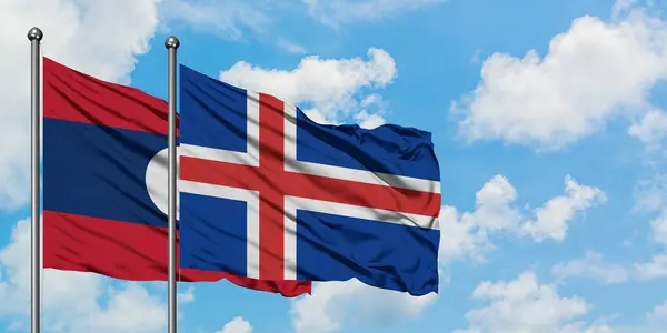 Bandera de Laos e Islandia ondeando en el viento contra el cielo azul nublado blanco juntos. Concepto diplomático, relaciones internacionales . — Foto de Stock