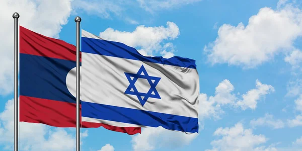 Bandera de Laos e Israel ondeando en el viento contra el cielo azul nublado blanco juntos. Concepto diplomático, relaciones internacionales . — Foto de Stock