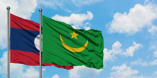 Bandera de Laos y Mauritania ondeando en el viento contra el cielo azul nublado blanco juntos. Concepto diplomático, relaciones internacionales . — Foto de Stock