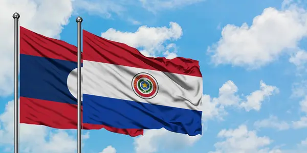 Лаос и парагвайский флаг вместе машут ветром против белого облачно-голубого неба. Концепция дипломатии, международные отношения . — стоковое фото