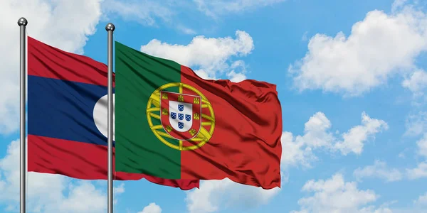 Laos och Portugal sjunker vifta i vinden mot vit grumlig blå himmel tillsammans. Diplomatisk koncept, internationella relationer. — Stockfoto