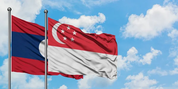 Laos e a bandeira de Singapura agitando no vento contra o céu azul nublado branco juntos. Conceito de diplomacia, relações internacionais . — Fotografia de Stock