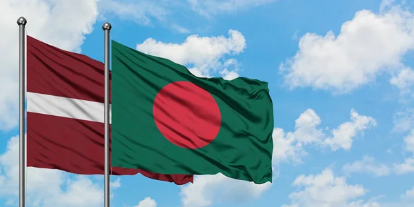 Bandera de Letonia y Bangladesh ondeando en el viento contra el cielo azul nublado blanco juntos. Concepto diplomático, relaciones internacionales . — Foto de Stock