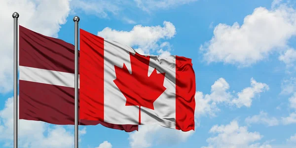 拉脱维亚和加拿大国旗在风中飘扬，白云蓝天相聚。外交概念、国际关系. — 图库照片