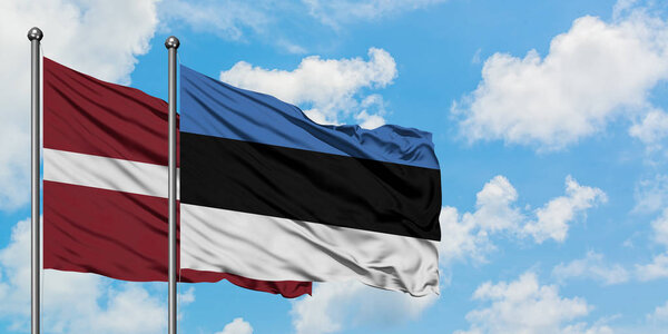 Latvia and Estonia flag waving in the wind against white cloudy blue sky together. Diplomacy concept, international relations.