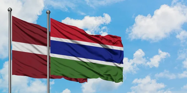 一緒に白い曇り青い空に対して風に手を振るラトビアとガンビアの旗。外交概念、国際関係. — ストック写真