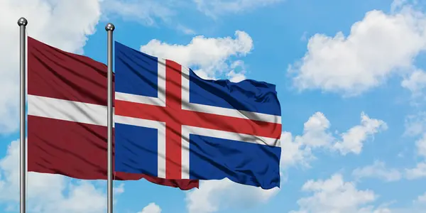 Латвия и Исландия вместе машут на ветру белым облачно-голубым небом. Концепция дипломатии, международные отношения . — стоковое фото