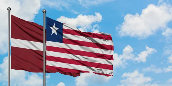 Łotwa i Liberia flaga machając w wiatr przed białym zachmurzone błękitne niebo razem. Koncepcja dyplomacji, stosunki międzynarodowe. — Zdjęcie stockowe