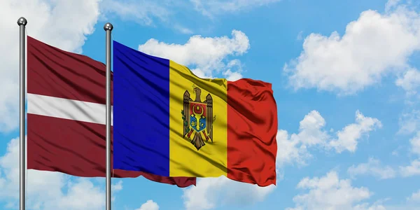 Bandera de Letonia y Moldavia ondeando en el viento contra el cielo azul nublado blanco juntos. Concepto diplomático, relaciones internacionales . — Foto de Stock