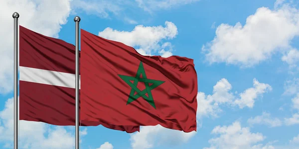 Bandera de Letonia y Marruecos ondeando en el viento contra el cielo azul nublado blanco juntos. Concepto diplomático, relaciones internacionales . — Foto de Stock