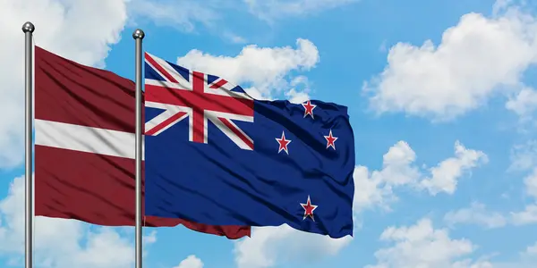 拉脱维亚和新西兰国旗在风中飘扬，与白云蓝天相一起。外交概念、国际关系. — 图库照片